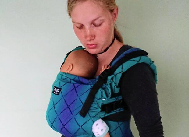 Slyngevejleder viser bæring af nyfødt dukke i bæresele