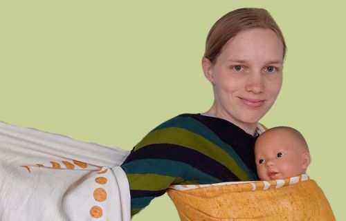 Rie portræt med dukke i fastvikle Portræt af Rie. Holder en dukke og en fastvikle, som hun er ved at stramme.